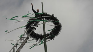 Bürgermeister Uwe Anke beim befestigen des Maibaumkranzes
